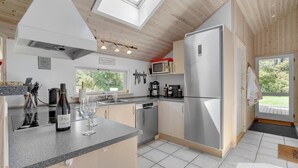 A modern kitchen with a large refrigerator, a microwave, and a coffee maker. There is a window providing natural light and a view of the outdoors. - Nice home in Væggerløse with sauna (Væggerløse)