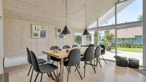 A dining area with a wooden table and black chairs, large windows, and a view of the outdoors. - Nice home in Væggerløse with sauna (Væggerløse)