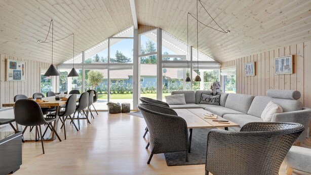 A spacious living area with a high ceiling, large windows, and a cozy seating arrangement. - Nice home in Væggerløse with sauna (Væggerløse)