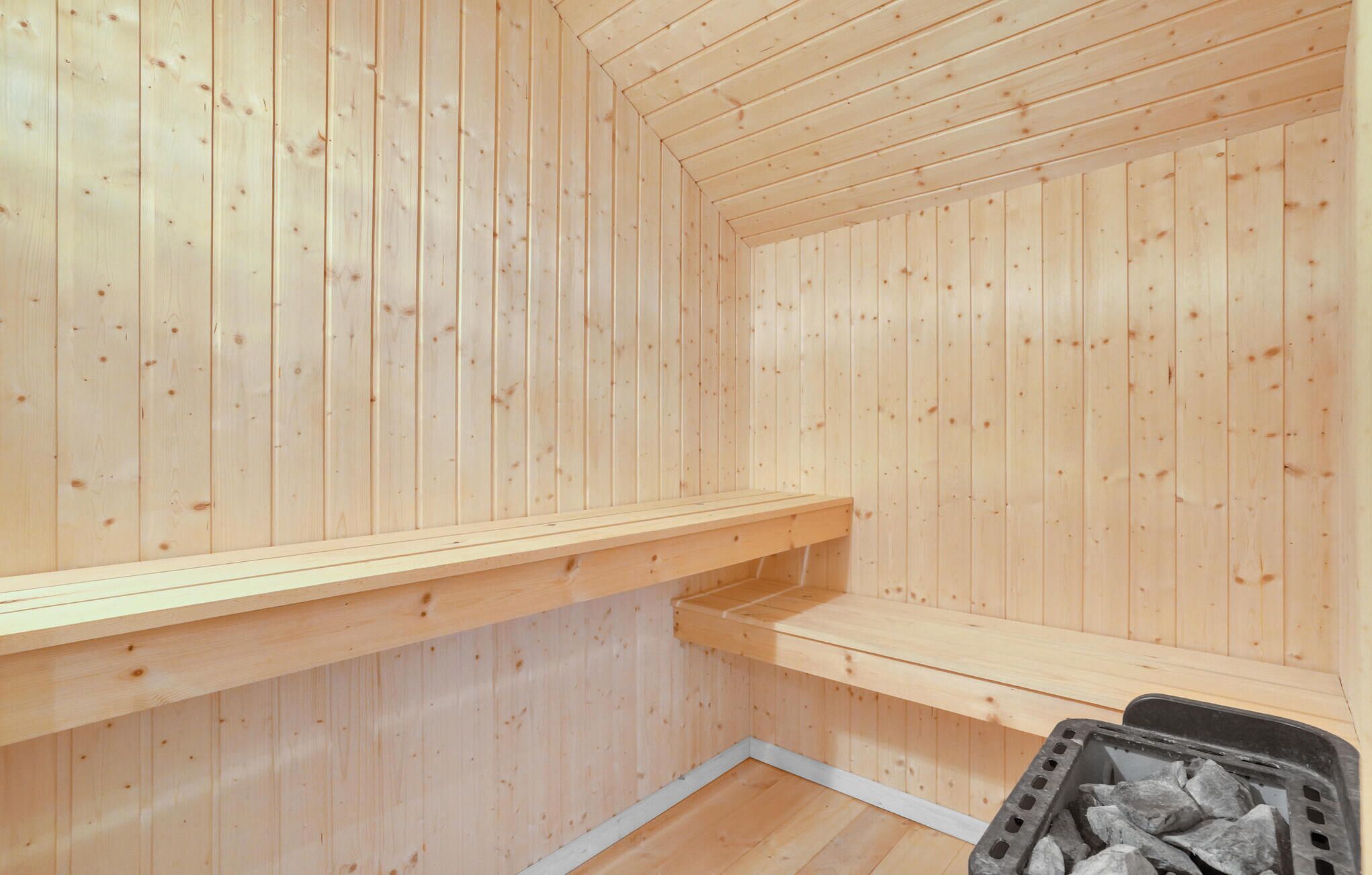 Un sauna avec des murs et des bancs en bois.