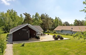 En træhytte med teksten 'Chillhouse 42', en terrasse, udendørs møbler og en have.