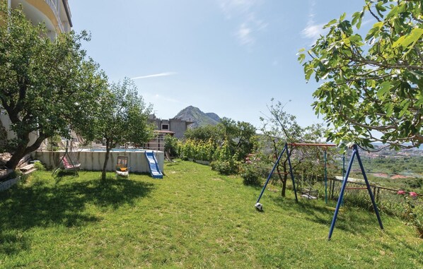 A backyard with a pool, a swing set, and a view of a mountain. - Cozy apartment in Zrnovnica with WiFi (Zrnovnica)