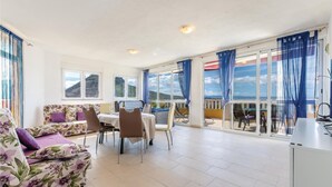 Una habitación amplia con balcón, zona de comedor y sofá.