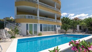 Un edificio de varios pisos con balcones, piscina y mobiliario de exterior.