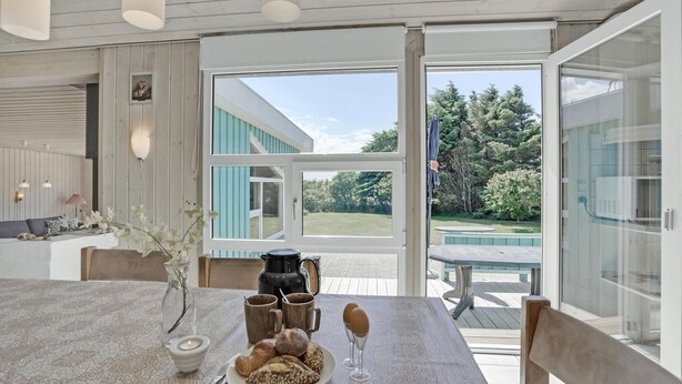 A dining area with a table set for breakfast, a view of the garden, and a modern interior design. - Awesome home in Løkken with sauna (Løkken)