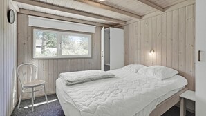 A bedroom with a bed, a chair, a wardrobe, and a window. - Awesome home in Løkken with sauna (Løkken)