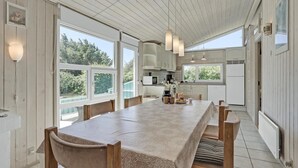 A spacious kitchen with a long table, wooden chairs, and pendant lights. - Awesome home in Løkken with sauna (Løkken)