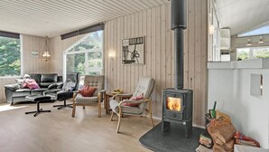 A cozy living room with a fireplace, wooden walls, and comfortable seating. - Awesome home in Løkken with sauna (Løkken)
