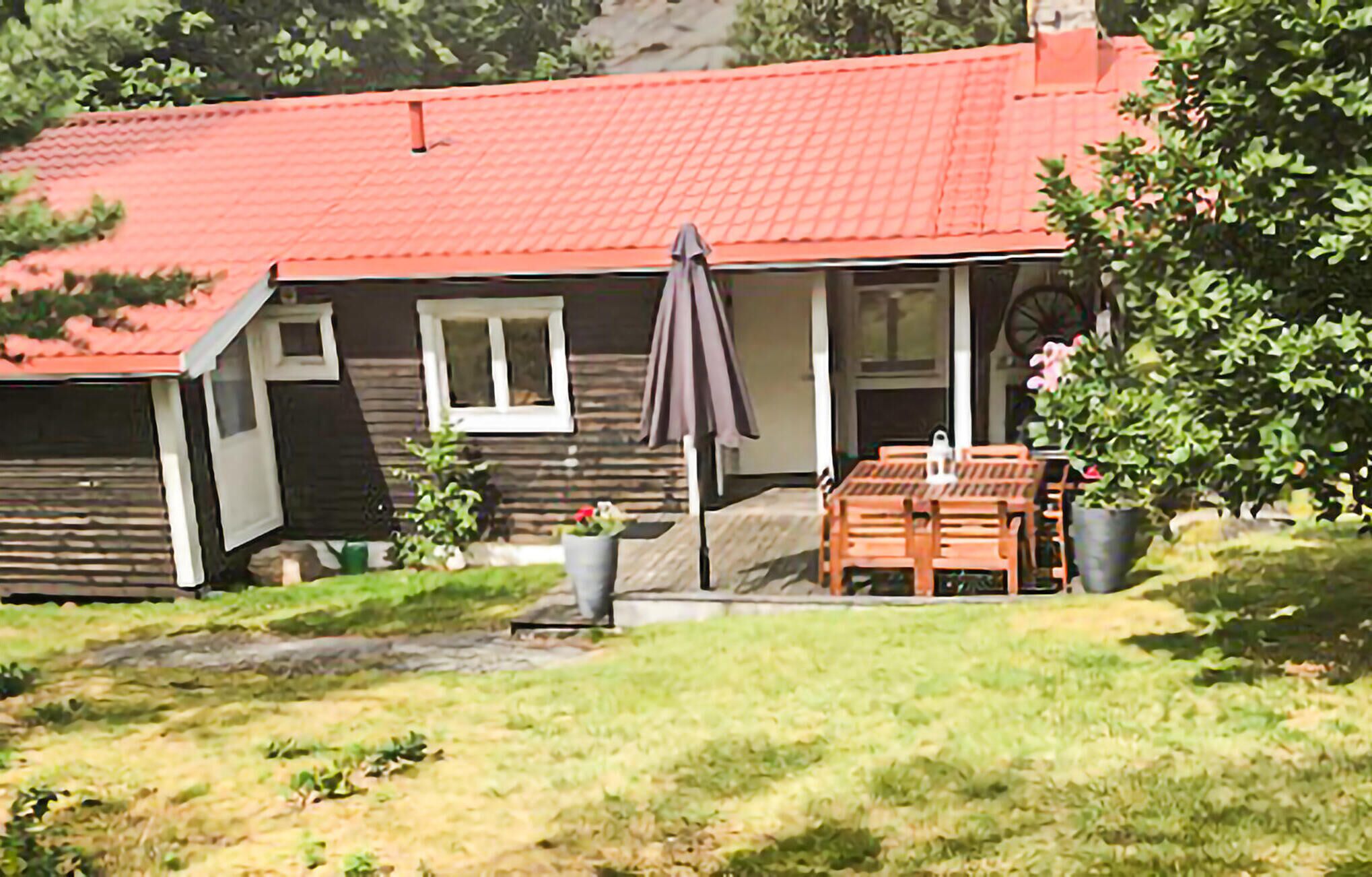 A house with a red roof, a porch with a table and chairs, and a garden area.
