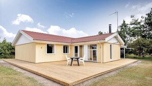A modern single-story house with a red-tiled roof, a wooden deck, and a glass door leading to an outdoor area. - 5 bedroom nice home in Væggerløse (Væggerløse)