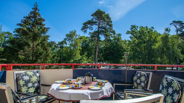 An outdoor seating area with a round table set for four, surrounded by chairs with floral upholstery. - Dune garden Whg. Wa45-50 - Wa45-50 (Kühlungsborn)
