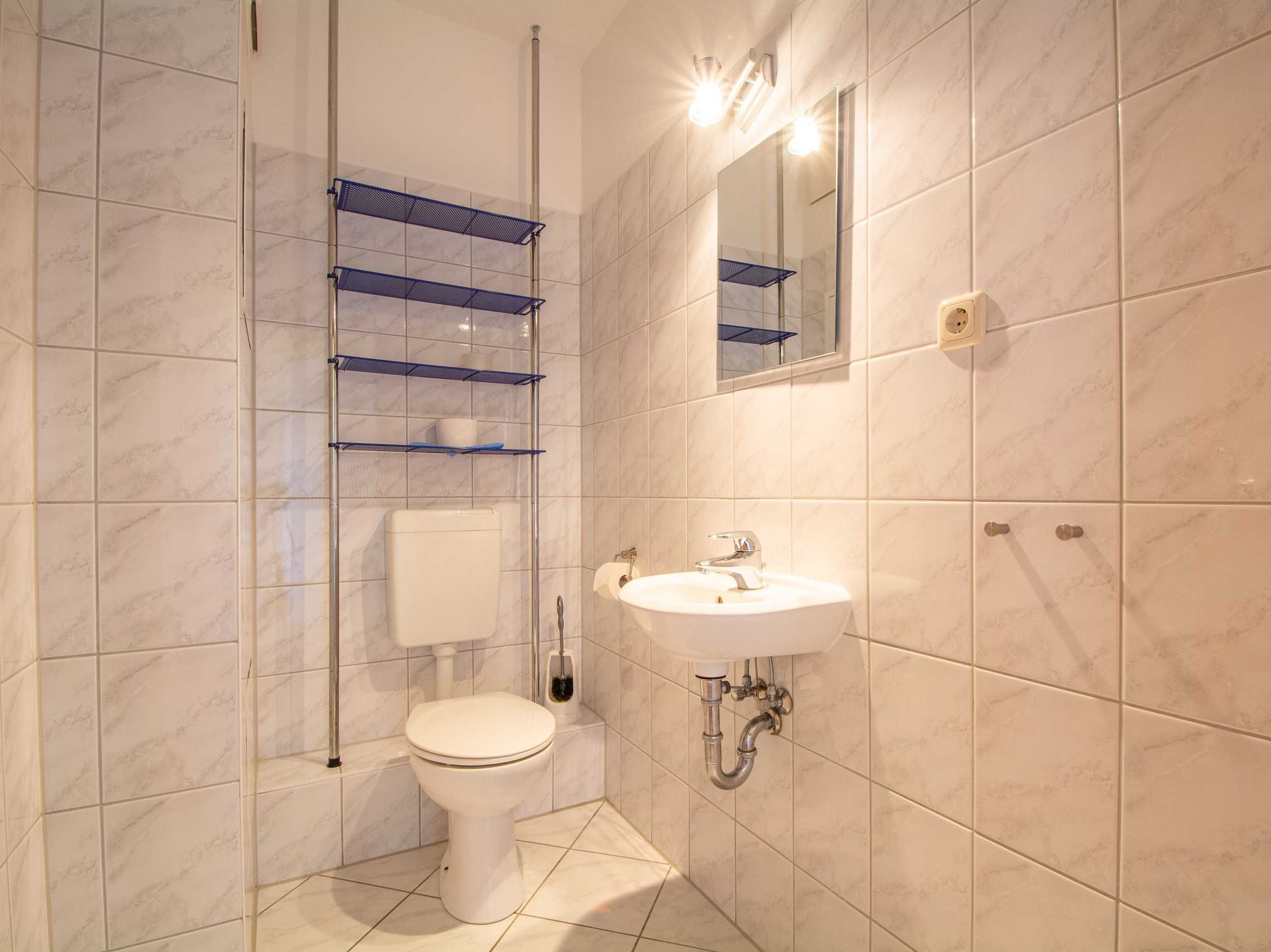 Een moderne badkamer met een toilet, wastafel en planken.