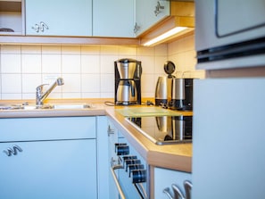 Eine moderne Küche mit einer Edelstahl-Spüle, einer Kaffeemaschine und einem Wasserkocher.