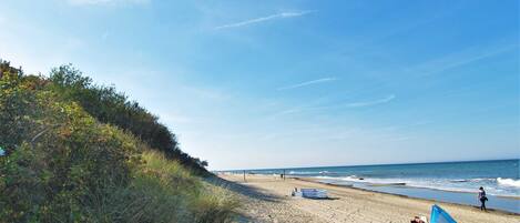 A beach with a tent and a striped blanket on the sand.
