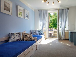 Ein Schlafzimmer mit zwei Betten, einem Schreibtisch und Blick ins Freie.
