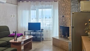 A living room with a sofa, a TV, a fireplace, and a window with curtains.