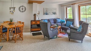 A living room with a sofa set, a dining table with chairs, a fireplace, and a large window with curtains. - Amazing home in Prerow with WiFi (Prerow)