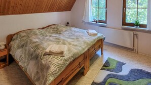 A bedroom with a wooden bed, a radiator, and a window with curtains. - Amazing home in Prerow with WiFi (Prerow)