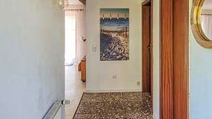 A hallway with a tiled floor, a painting of a coastal scene, and a wooden door. - Amazing home in Prerow with WiFi (Prerow)