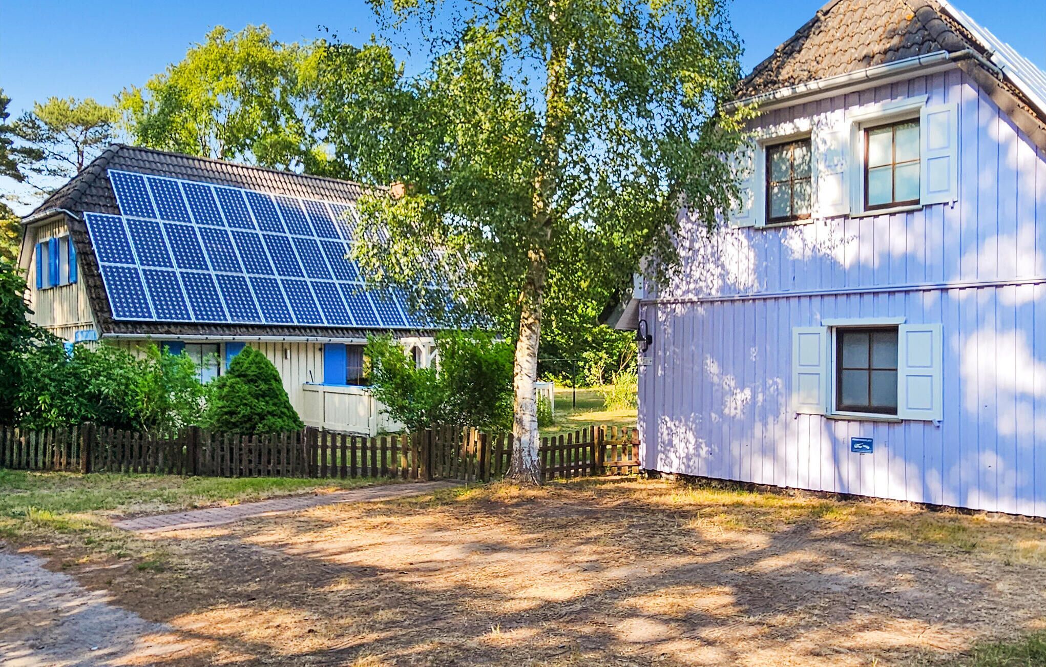 A house with a solar panel array on the roof and a separate building with a window.