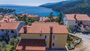 A coastal village with terracotta-roofed buildings, a clear view of the sea, and lush green hills in the background. - 2 bedroom amazing apartment in Rabac (Rabac)
