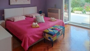 A bedroom with a large bed, pillows, a bedside table, a nightstand, a window, and a view of greenery outside. - 2 bedroom amazing apartment in Rabac (Rabac)