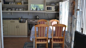 A compact kitchen with wooden cabinets, a stove, and a microwave. There are two wooden chairs with patterned upholstery. - 3 bedroom awesome home in Lyngdal (Lyngdal)