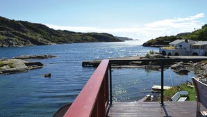 A wooden pier extending into calm waters with rocky shores and a small white building on the right. - 3 bedroom awesome home in Lyngdal (Lyngdal)