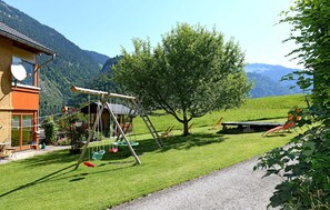 A house with a swing set, a tree, and a view of mountains.