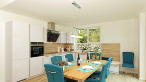 Eine moderne Küche mit weißen Schränken, einem Holztisch und blauen Stühlen.