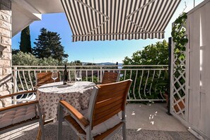 Eine Terrasse mit Tisch und Stühlen, einem Weinglas und Blick auf die Landschaft.