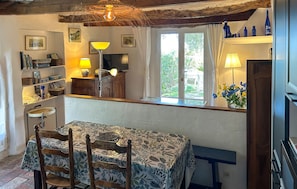 Un coin repas comprenant une table, des chaises, une lampe et une fenêtre donnant sur un paysage agréable.