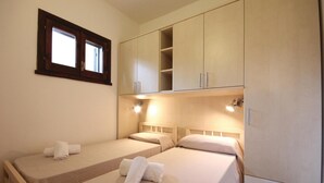 A bedroom with two beds, a window, and built-in cabinets.