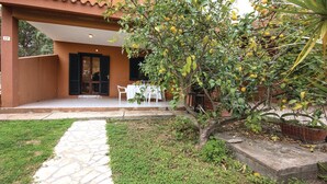 A courtyard with a stone pathway leading to a covered seating area with tables and chairs.
