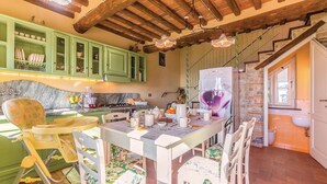 A kitchen with green cabinets, a dining table with chairs, a refrigerator, and a sink.
