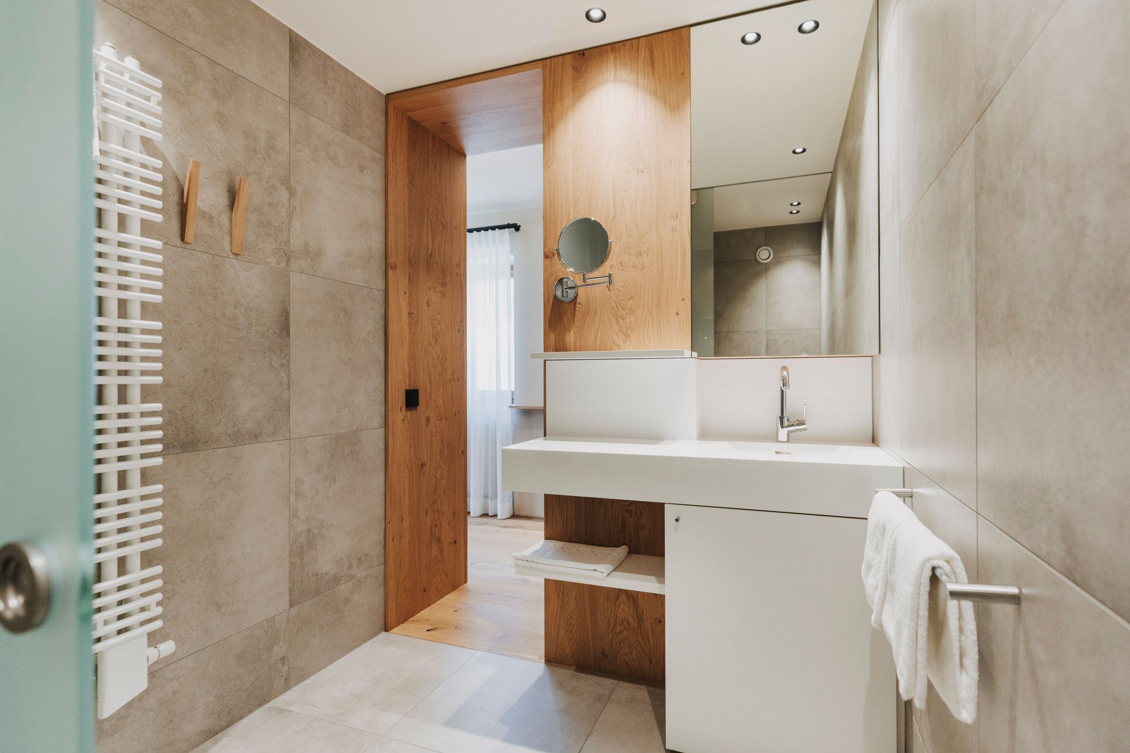 Un baño moderno con tocador de madera, espejo y perchero.