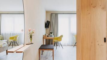 A modern room with a wooden bench, two yellow chairs, a small table, and a mirror.