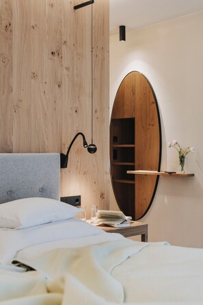 Une chambre à coucher comprenant un lit, une table de chevet, un miroir et une armoire en bois.