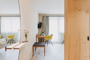 Une pièce moderne avec un banc en bois, deux chaises jaunes, une petite table et un miroir.