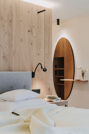 Une chambre à coucher comprenant un lit, une table de chevet, un miroir et une armoire en bois.