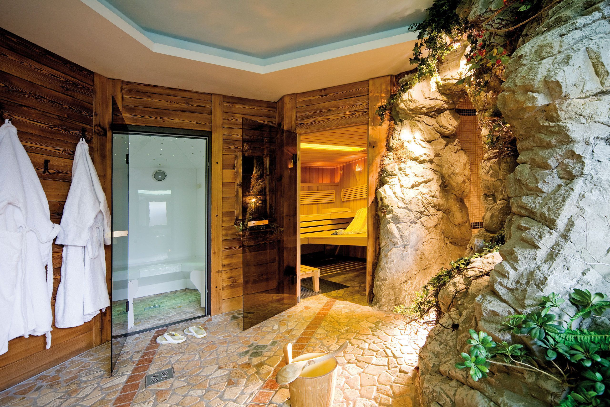 Un interior de madera con pared de piedra, puerta de cristal y un banco.