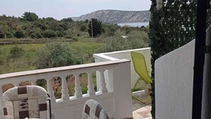 A balcony with a table and chairs, overlooking a grassy area and a body of water.