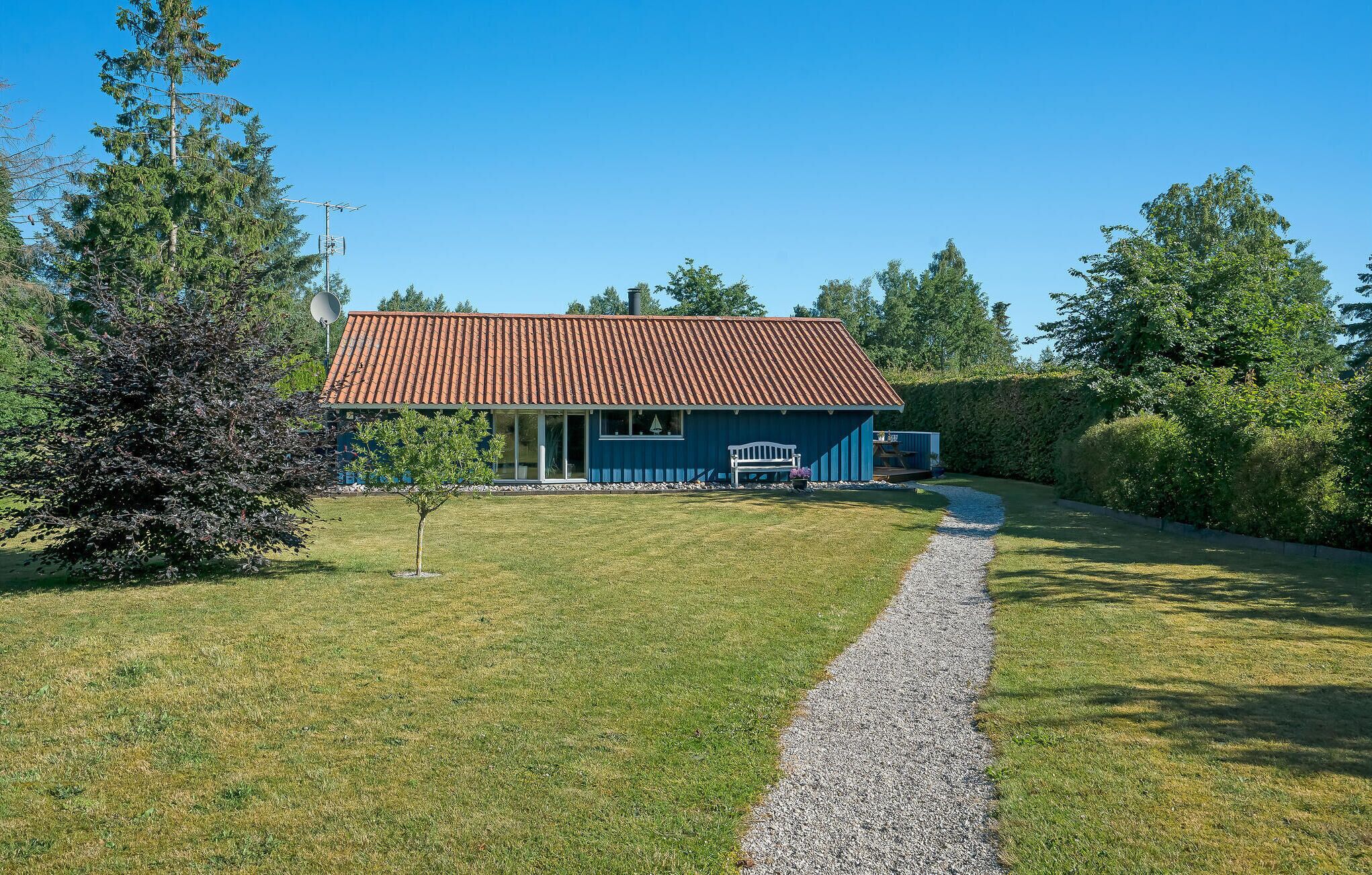 Een huis met een rood dak, een grindpad en een kleine tuin.