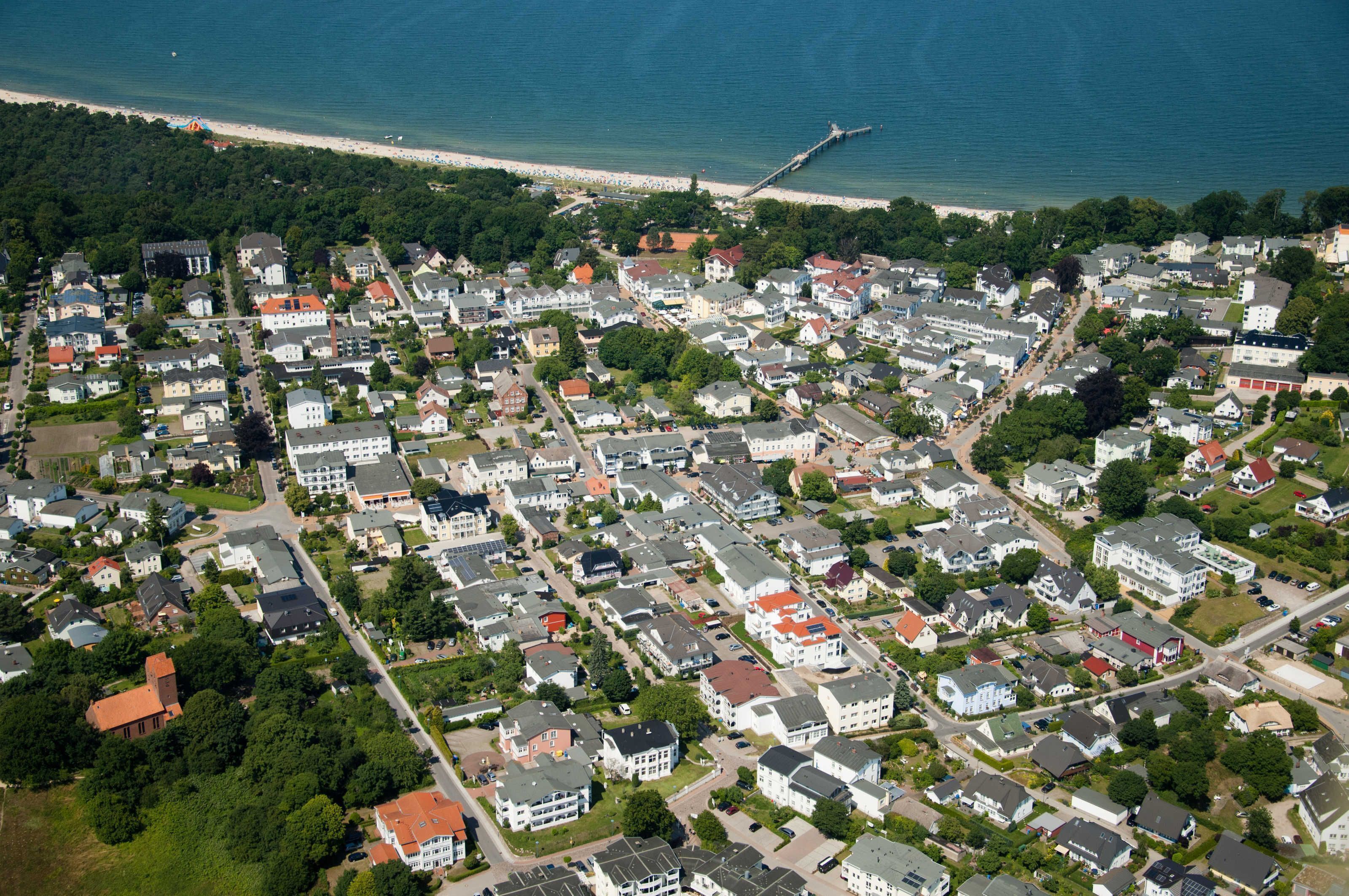Eine Luftaufnahme eines Wohngebiets mit Häusern, Straßen und einem Steg, der sich ins Wasser erstreckt.