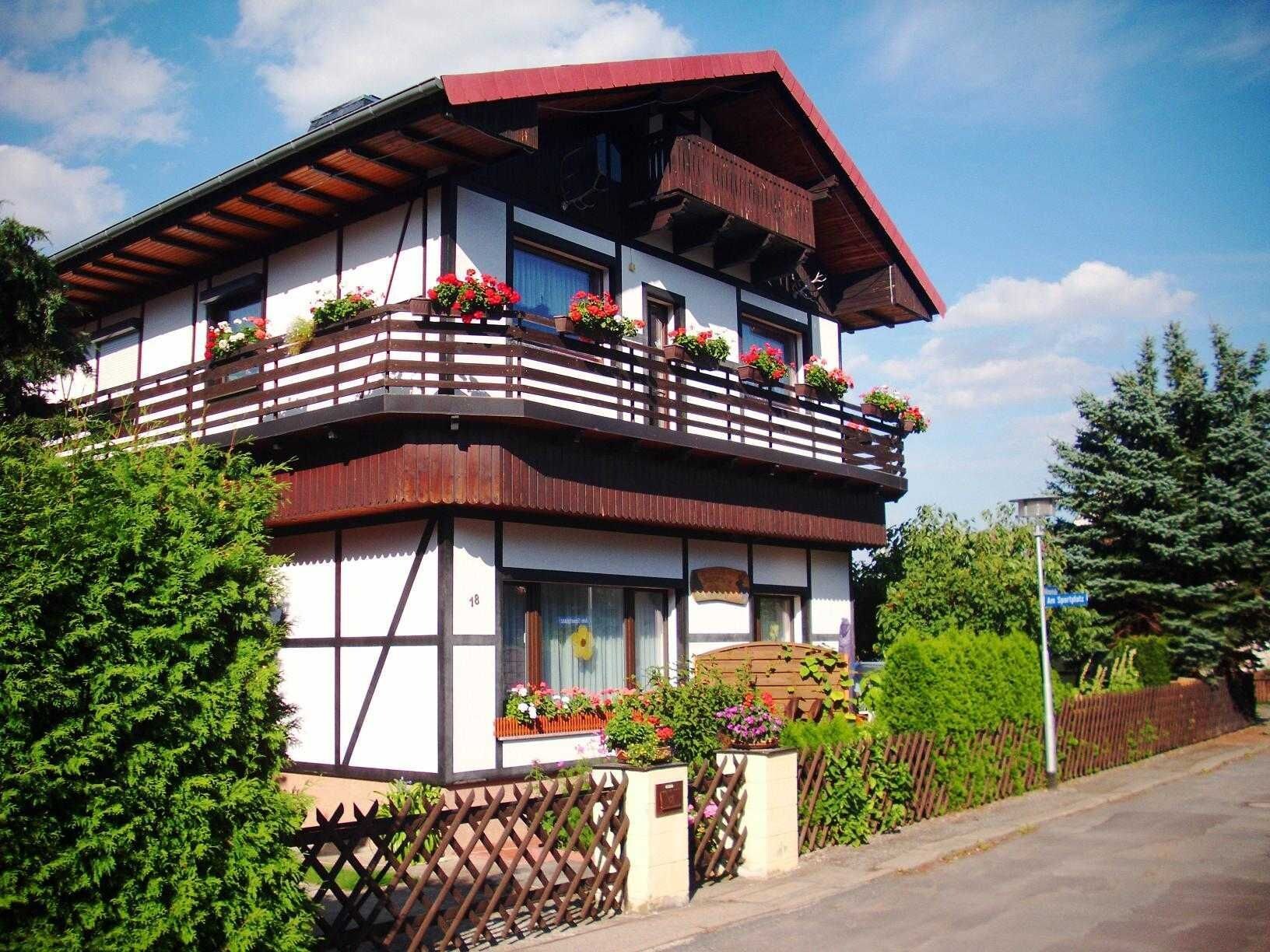 Ein zweistöckiges Gebäude mit Balkonen, einem Holzzaun und blauem Himmel.