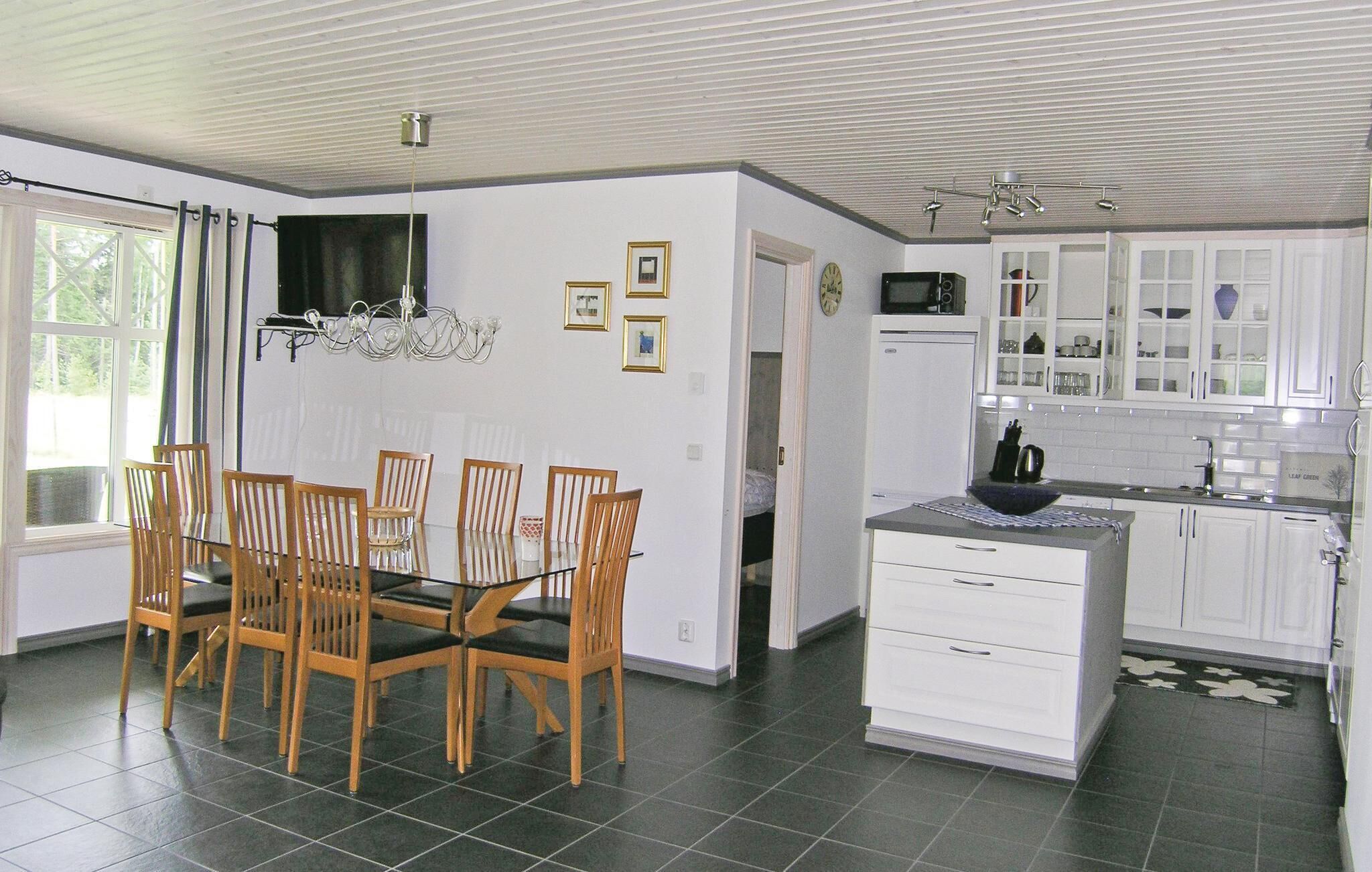 Une cuisine moderne avec des meubles blancs, un coin repas avec des chaises en bois et un lustre.