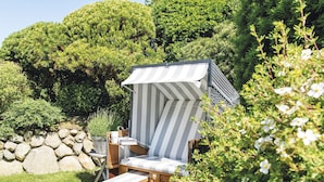 Une terrasse en bois avec une chaise à baldaquin à rayures et une petite table.