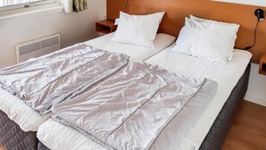 A neatly made bed with a grey and white duvet, a wooden headboard, and bedside lamps.