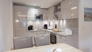 Eine moderne Küche mit Mikrowelle, Kaffeemaschine, Toaster und Spüle. Zwei Stühle und ein Tisch mit einer Dekoration.