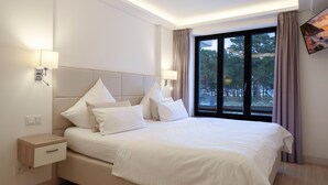 Ein modernes Schlafzimmer mit einem großen Bett, zwei Nachttischen, einem Beistelltisch und einem Fenster mit Vorhängen.